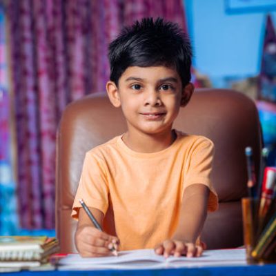 Little young boy doing his school homework or writing on notebook at home on his study table. Concept of Homeschooling and Study at home.